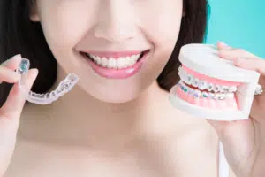 Patient holding a clear aligner and dental model demonstrating what are invisalign attachments in orthodontic treatment